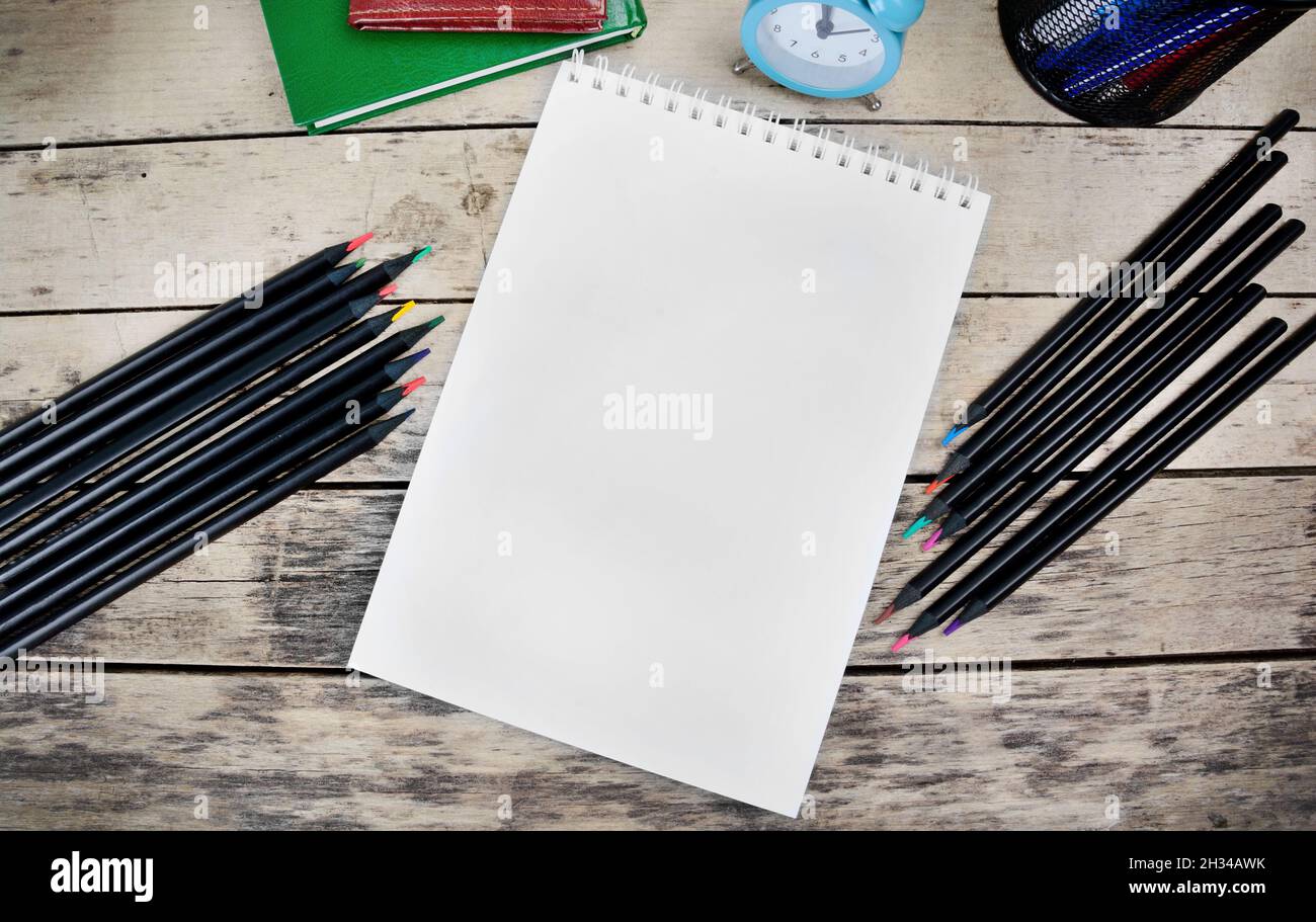 Empty notebook with pencils and alarm clock on wooden desk Stock Photo