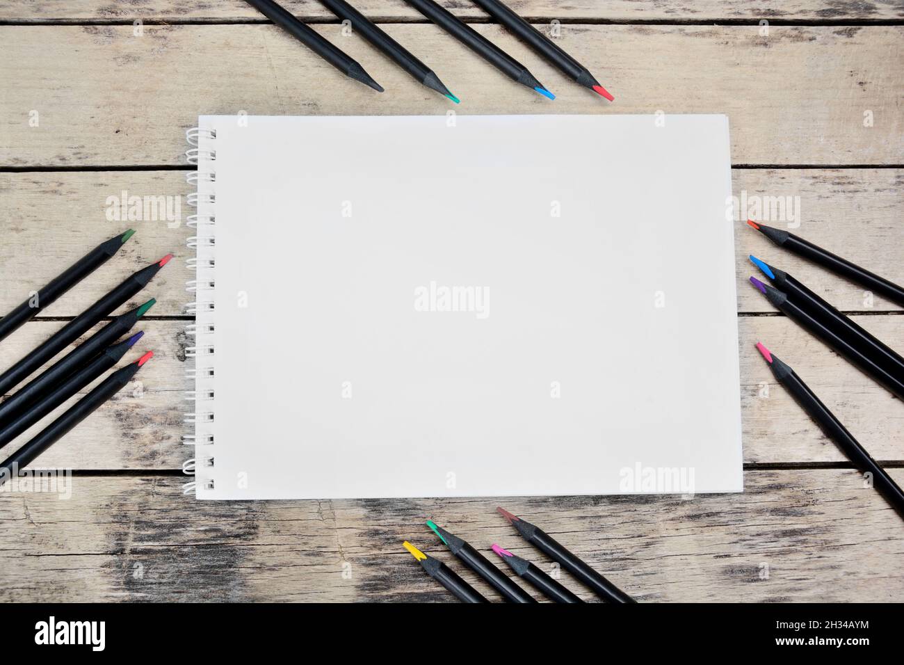Empty notebook with black colorul pencils on desk Stock Photo