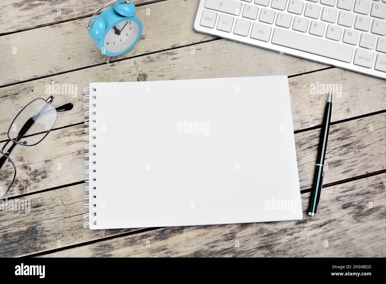 Blank notepad, glasses, keyboard, pen and glasses on a desk Stock Photo