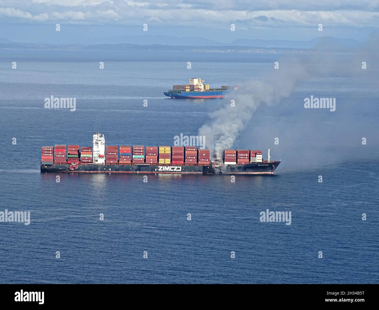 Victoria, Canada. 23rd Oct, 2021. The commercial cargo ship MV ZIM Kingston, burns after losing 40 shipping containers during transit in the Strait of Juan de Fuca October 23, 2021 near Victoria, British Columbia, Canada. The shipping containers were carrying potassium amylxanthate which ignited. Credit: PO3 Diolanda Caballero/U.S. Coast Guard/Alamy Live News Stock Photo