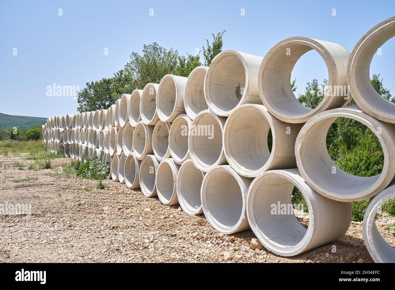 Stack of drainage concrete pipe for septic tanks and wells. Stock Photo