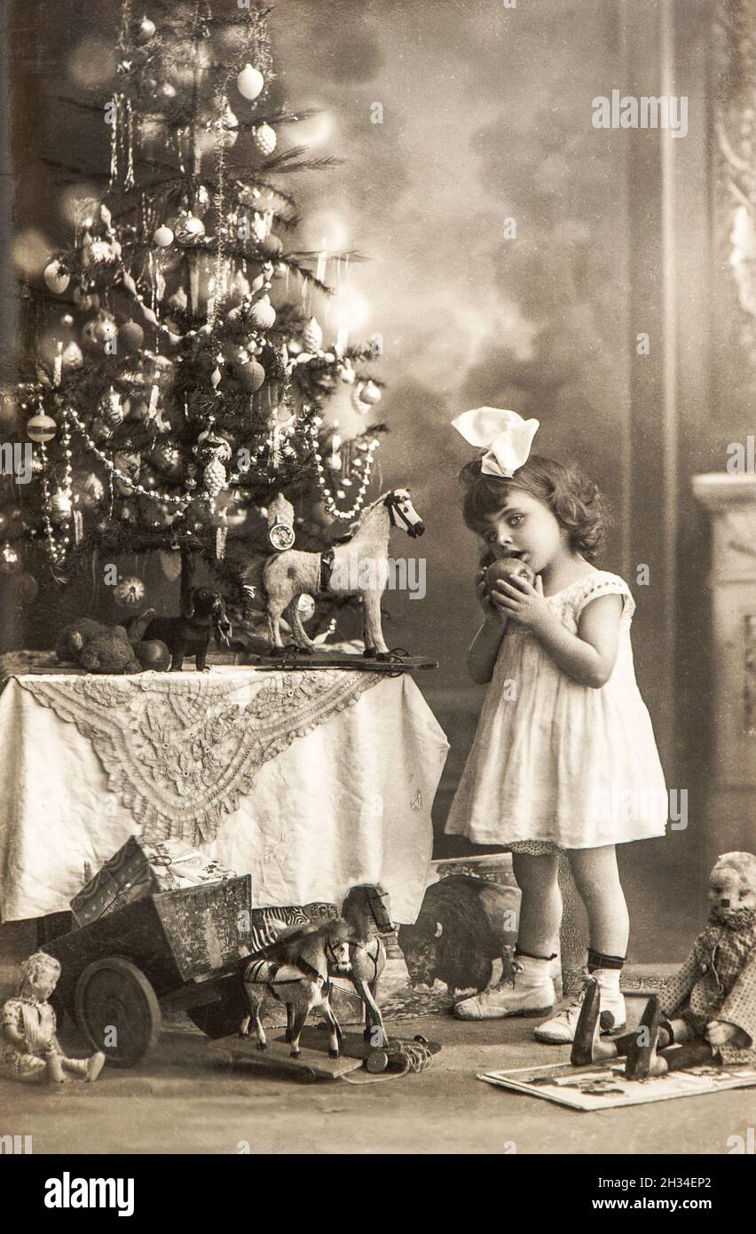 Littele girl with Christmas tree and vintage toys. Old photo postcard Stock Photo