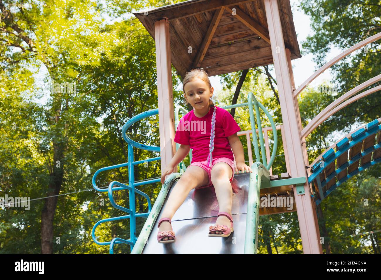 The little girl is sitting on a slide in the playground Stock Photo - Alamy