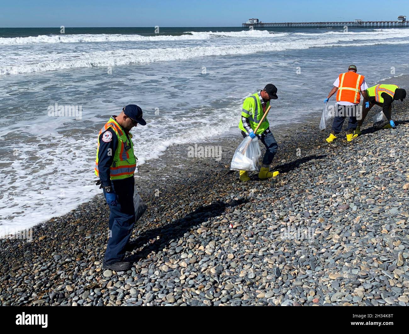 Oceanside Harbor Beach, United States. 12 October, 2021. U.S. Coast Guard and contract workers clean tar balls off Oceanside Harbor Beach following an offshore oil spill October 12, 2021 in San Diego County, California. An estimated 144,000 gallons spiked from a pipeline off Huntington Beach on October 1st.  Credit: PO3 Alex Gray/U.S. Coast Guard/Alamy Live News Stock Photo