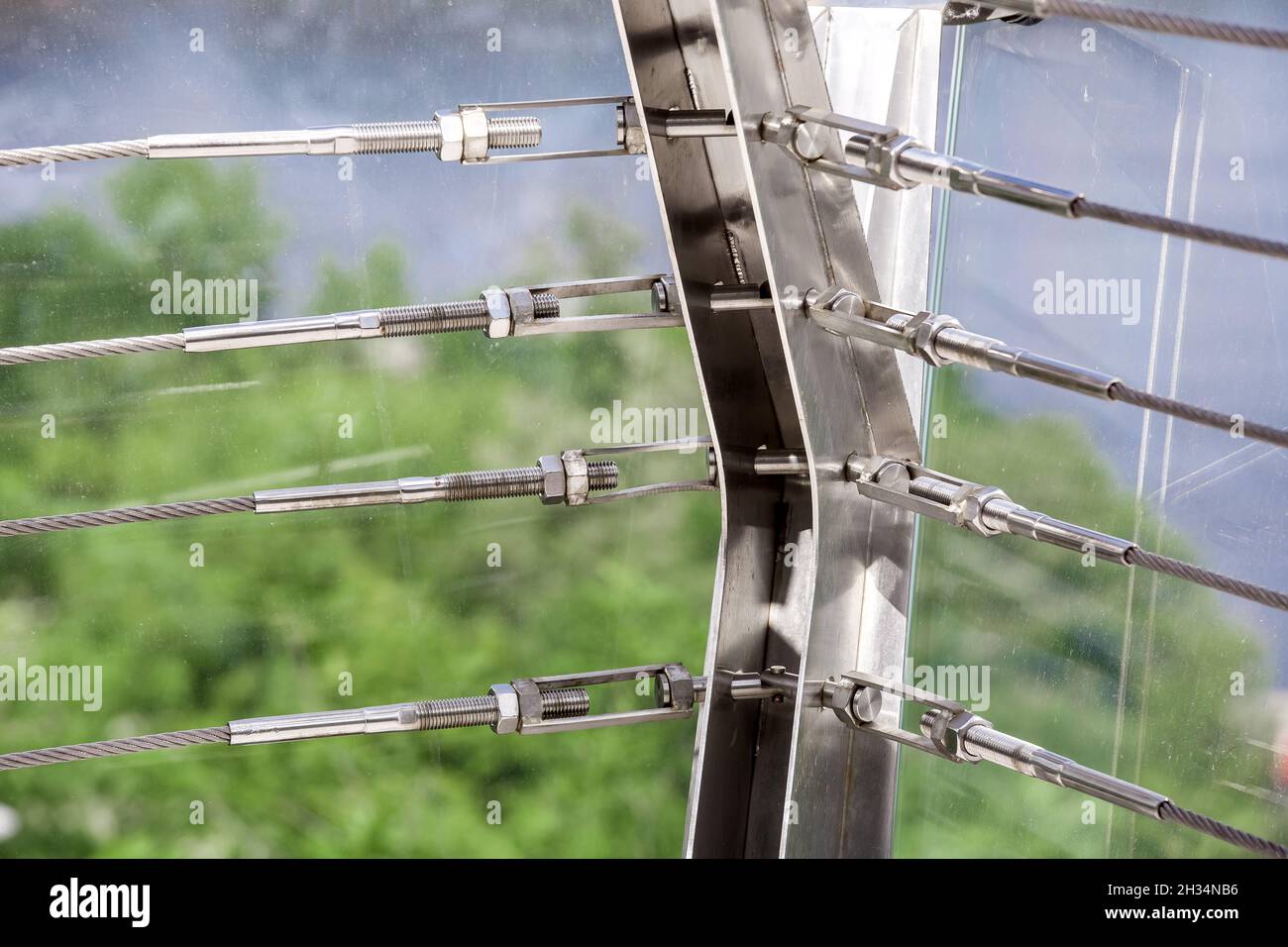 A close up view of lock sling steel and screw, a detail of frame on glass bridge with fastening engineering construction stainless steel turnbuckle. Stock Photo