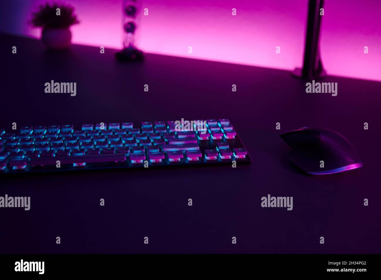 Low light scene of computer input devices, pink illuminated wall in