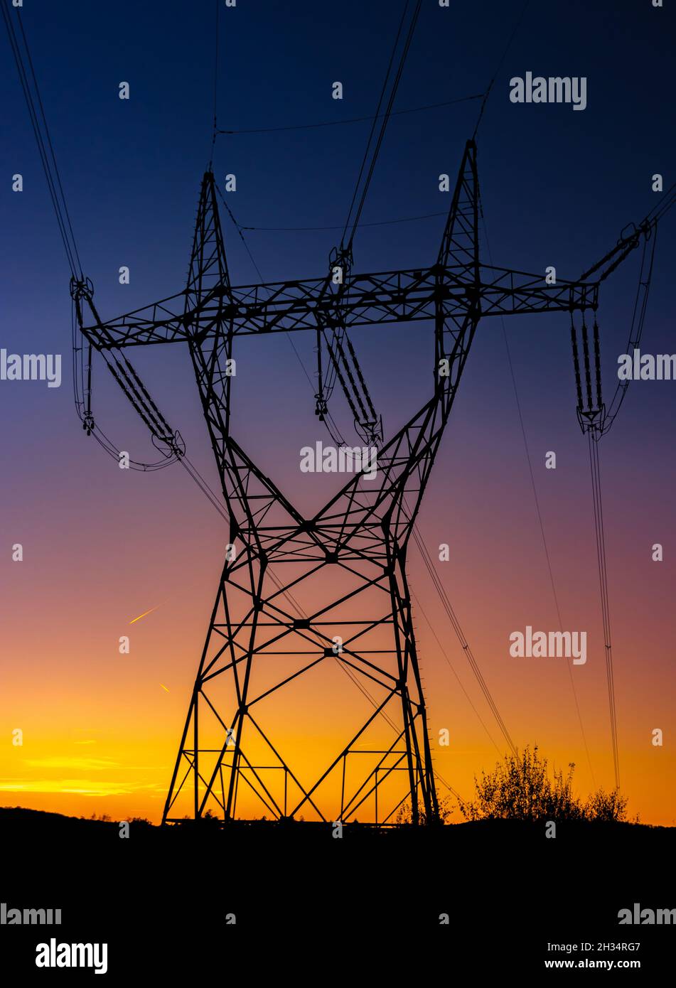 Silhouette of a high voltage tower with the sunset on a background ...