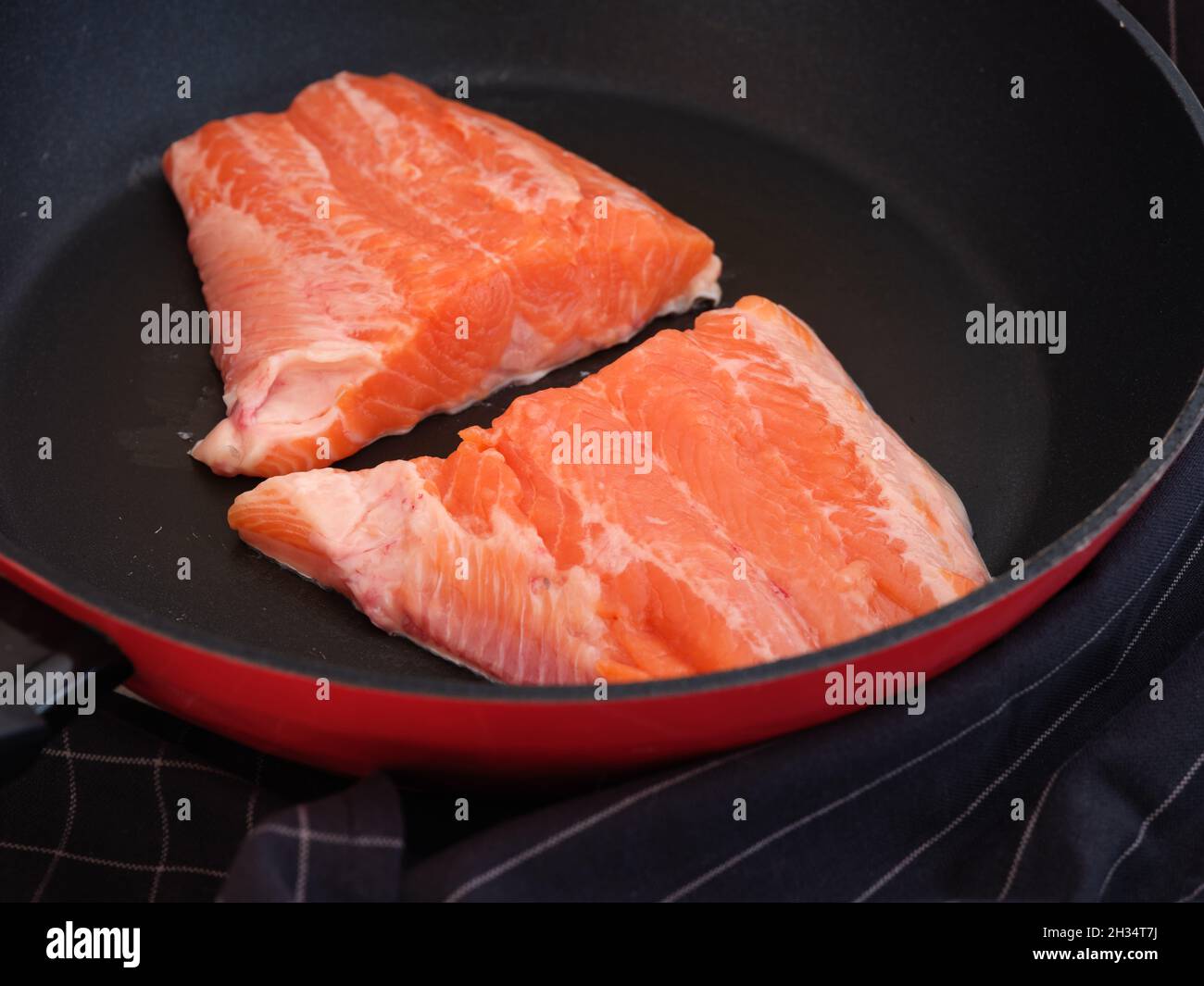 Two trout fillet slices lying in a frying pan ready to be cooked. Low key. Close up. Stock Photo