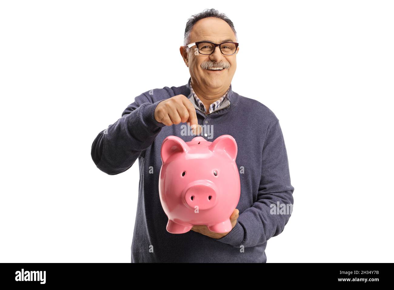 Mature man putting a coin into a piggy bank and smiling at camera ...