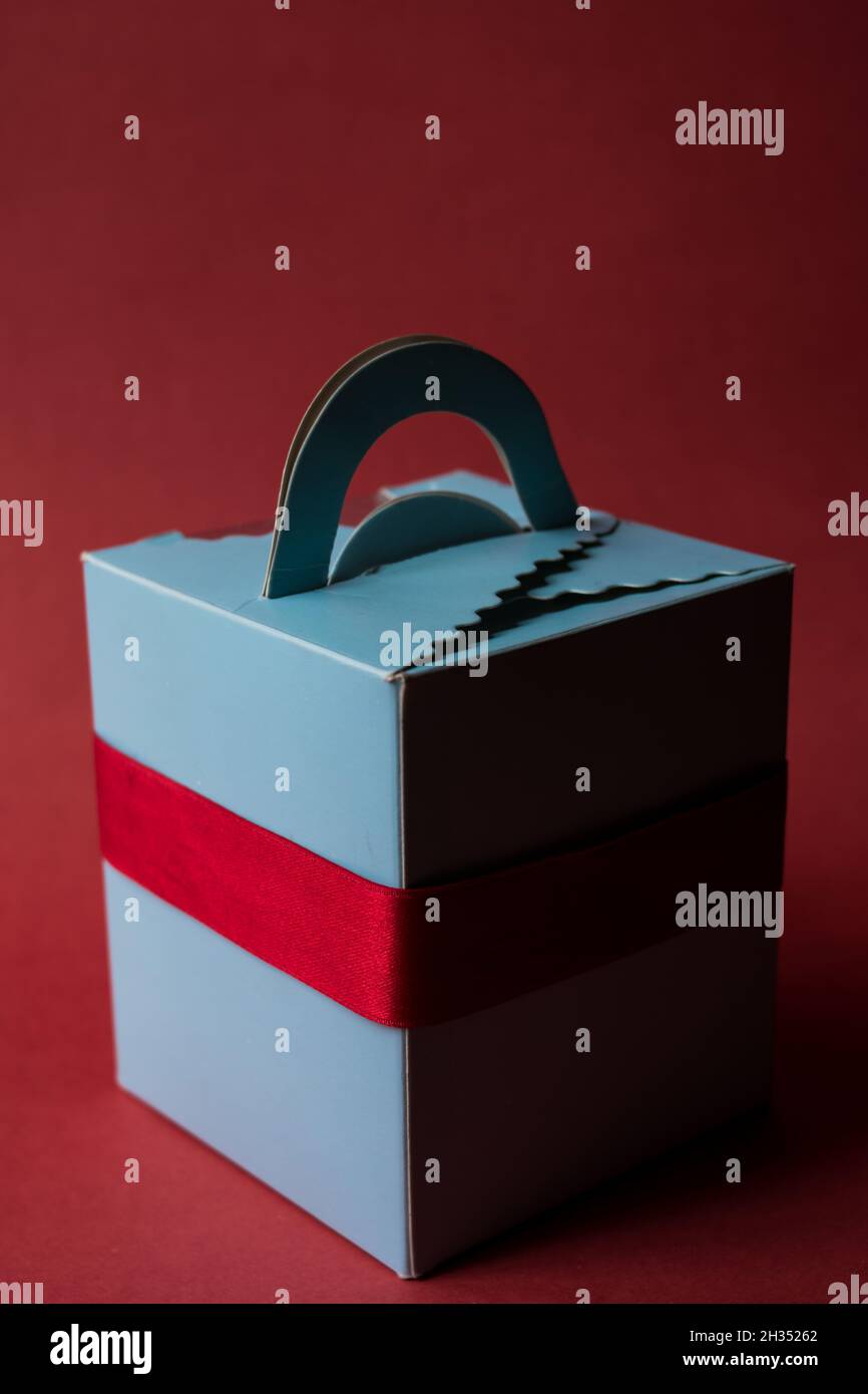 Blue gift box with a red ribbon on a red background Stock Photo