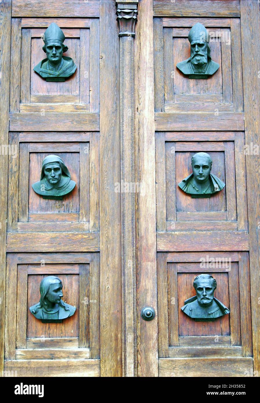 The main door of the Basilica of S. Marriacki, known as St. Mary's Basilica,  is adorned with sculptures depicting heads of apostles, Polish saints and prophets in Krakow, Poland.  The church, re-built in the 14th Century, doors were completed in 1929 with the sculptures created by Karol Hukan. Stock Photo