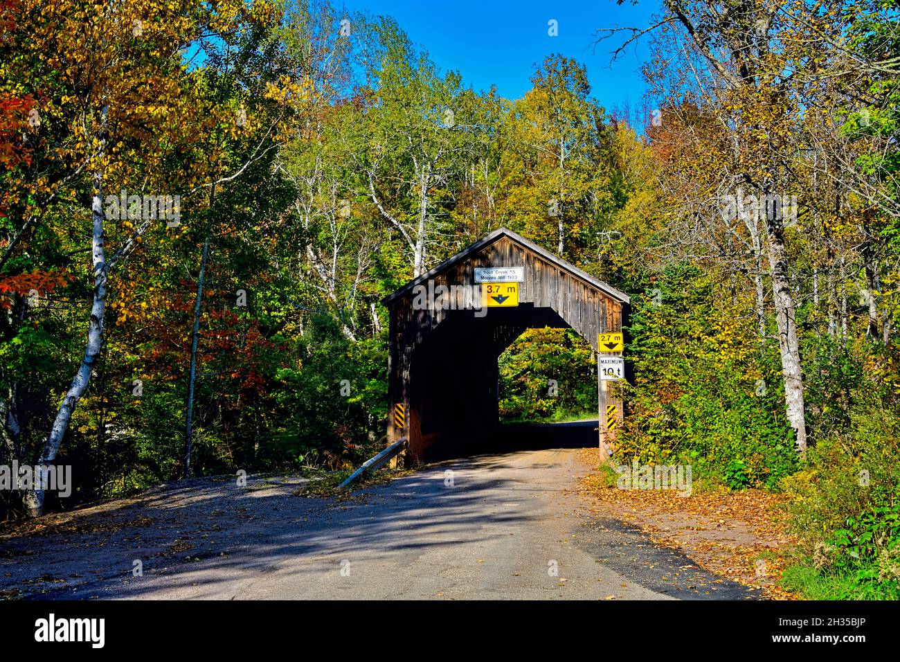 An autumn landscape image  of Trout Creek #5 covered bridge on a rural road near Waterford New Brunswick Canada. Stock Photo