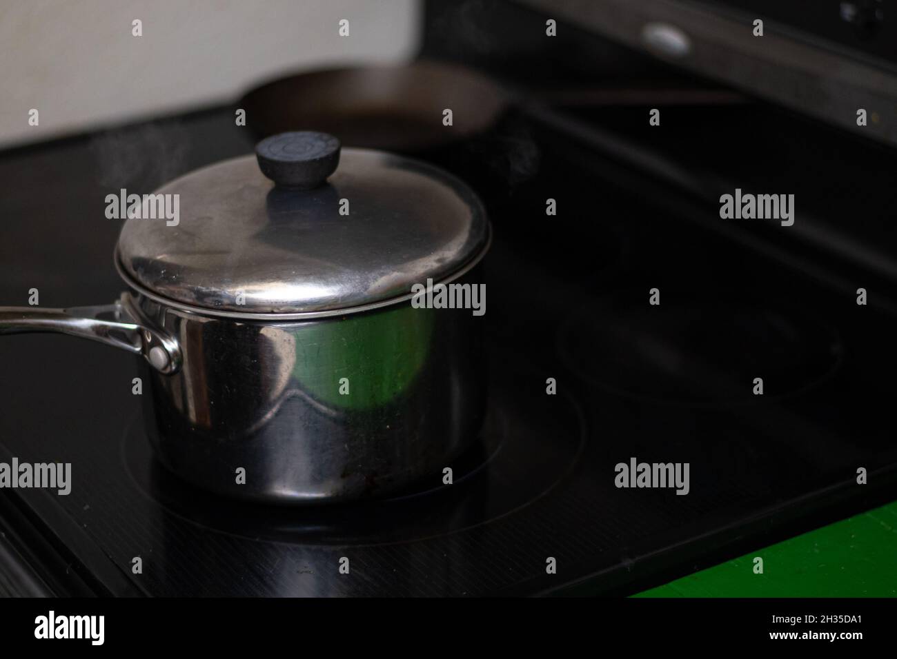 Steaming pot with lid on black stove Stock Photo Alamy