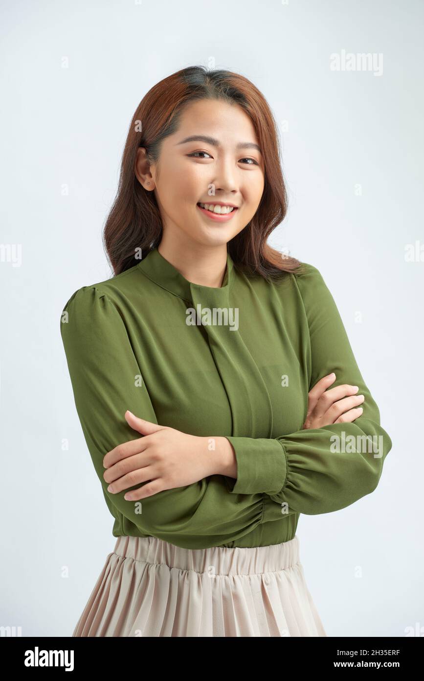 Beautiful young woman in smart casual wear keeping arms crossed and smiling while standing against grey background Stock Photo