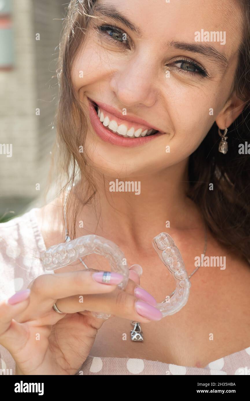 Beautiful caucasian woman holding transparent mouth guards for bite