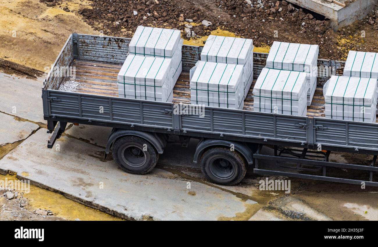 Stacks of new white sand-lime bricks in the back of a truck were taken to the construction site. Delivery of building materials. Stock Photo