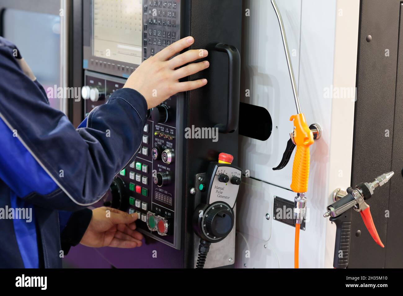Worker adjusts the parameters of the CNC machine. Selective focus. Stock Photo