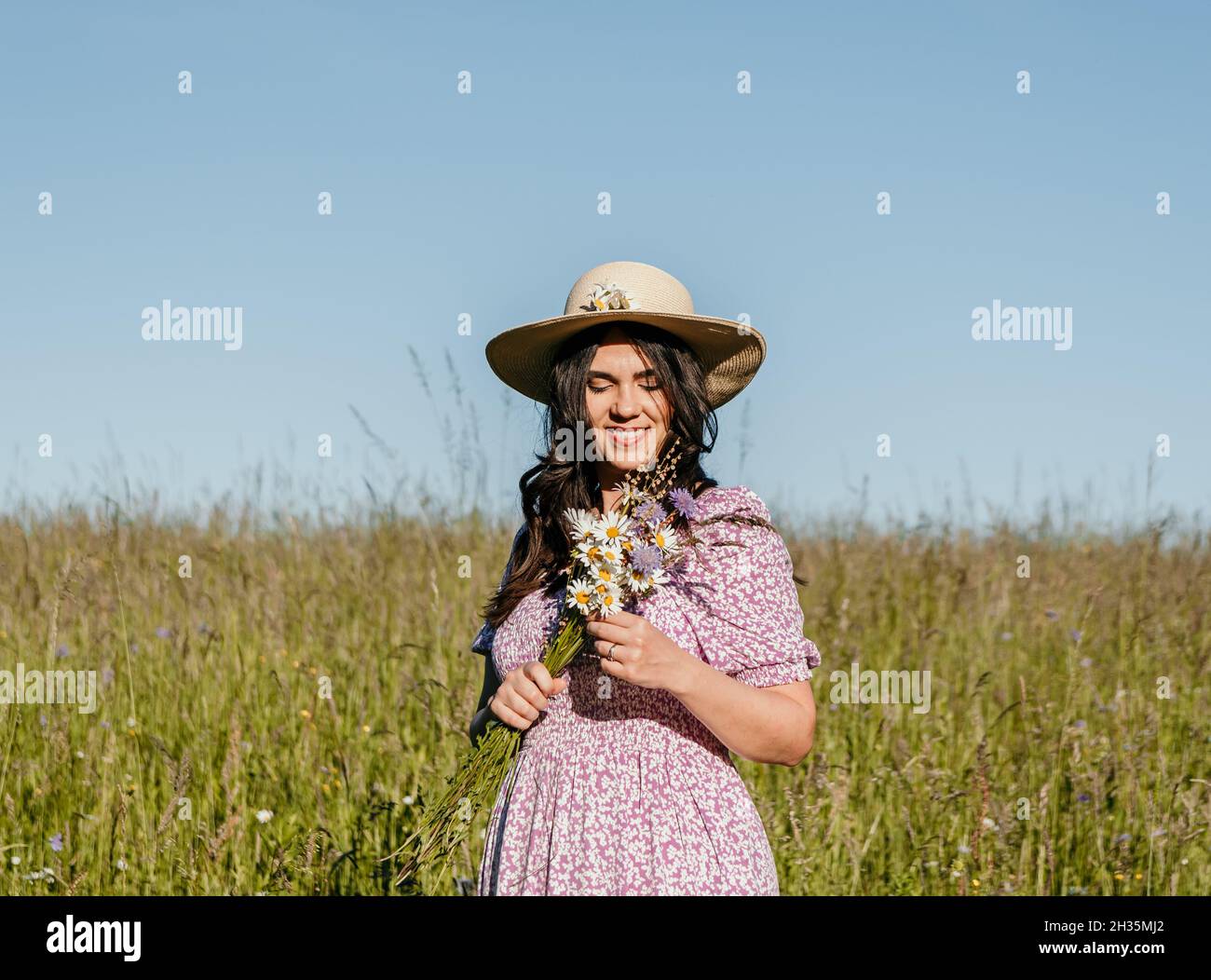 Girl standing in field holding flowers hi-res stock photography and ...
