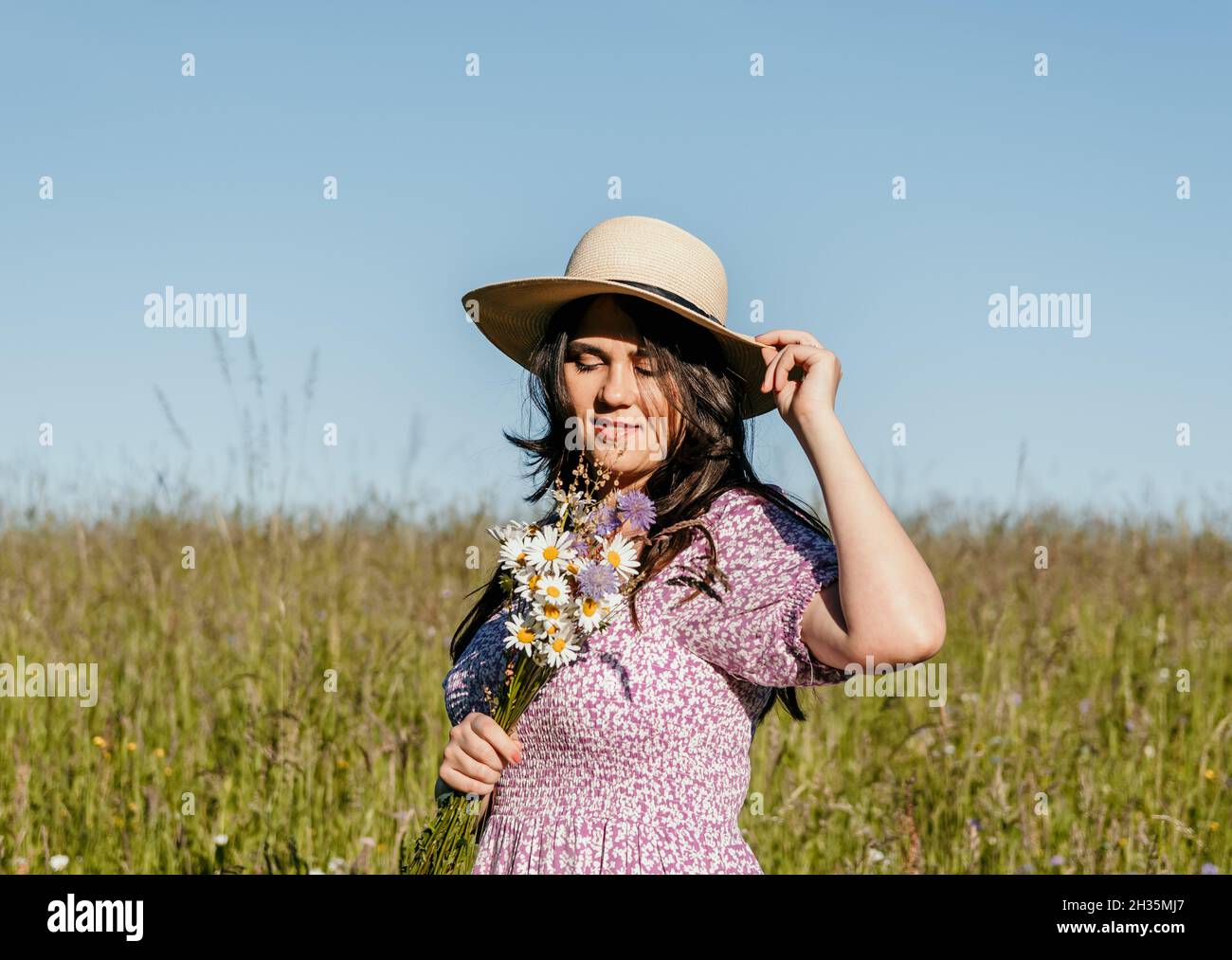 Girl standing in field holding flowers hi-res stock photography and ...