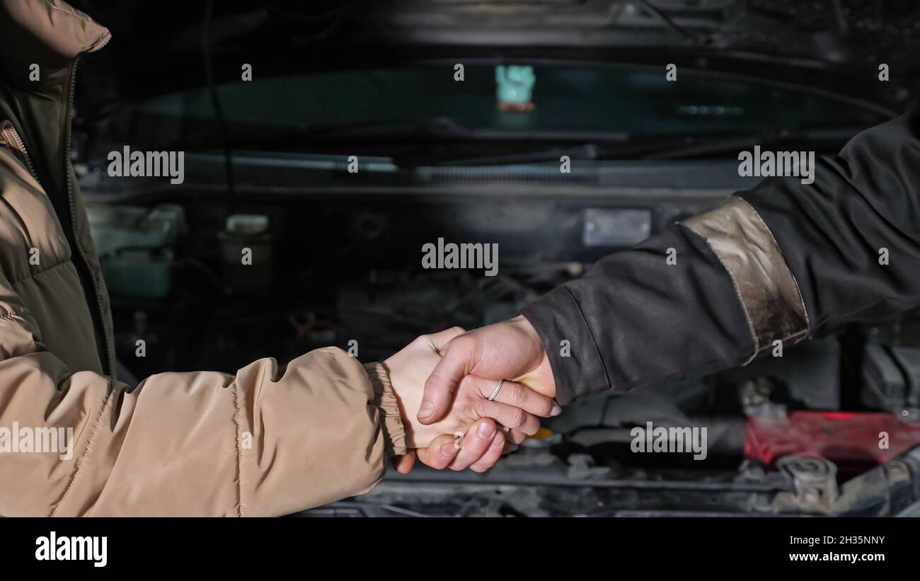 Worker and woman client shake hands near broken car closeup Stock Photo