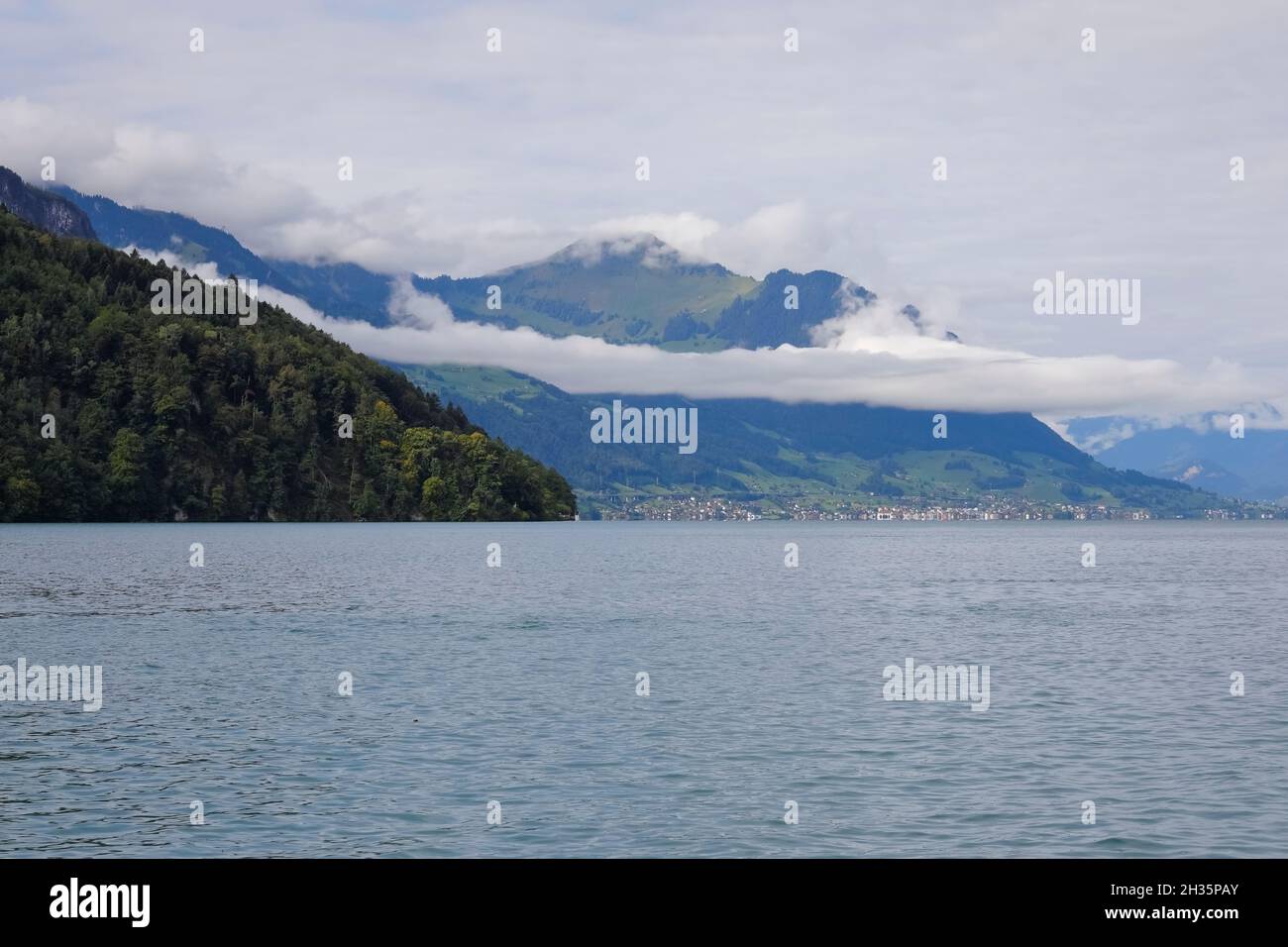 The cloud is seen over the mountain landscape at Lake Lucerne in Switzerland. The small town of Beckenried is located on the lakeshore. Stock Photo