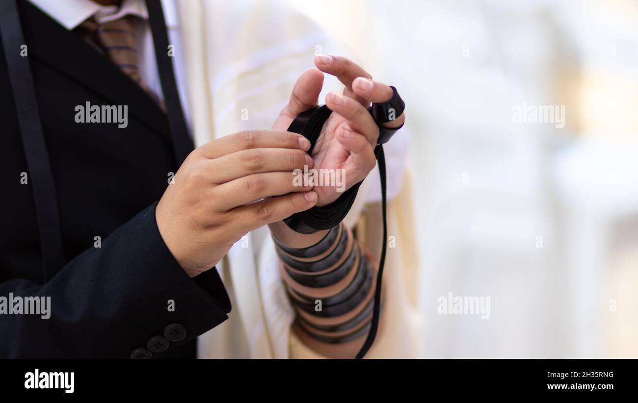 03-10-2021. jerusalem-israel.  A close-up of a Jewish bar mitzvah boy, wearing a white shirt And a black suit, put s tefillin for the first time in th Stock Photo