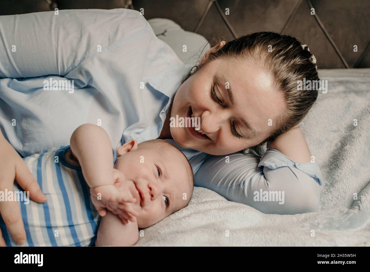 Young mother cuddling with her newborn baby boy in bed Stock Photo Alamy