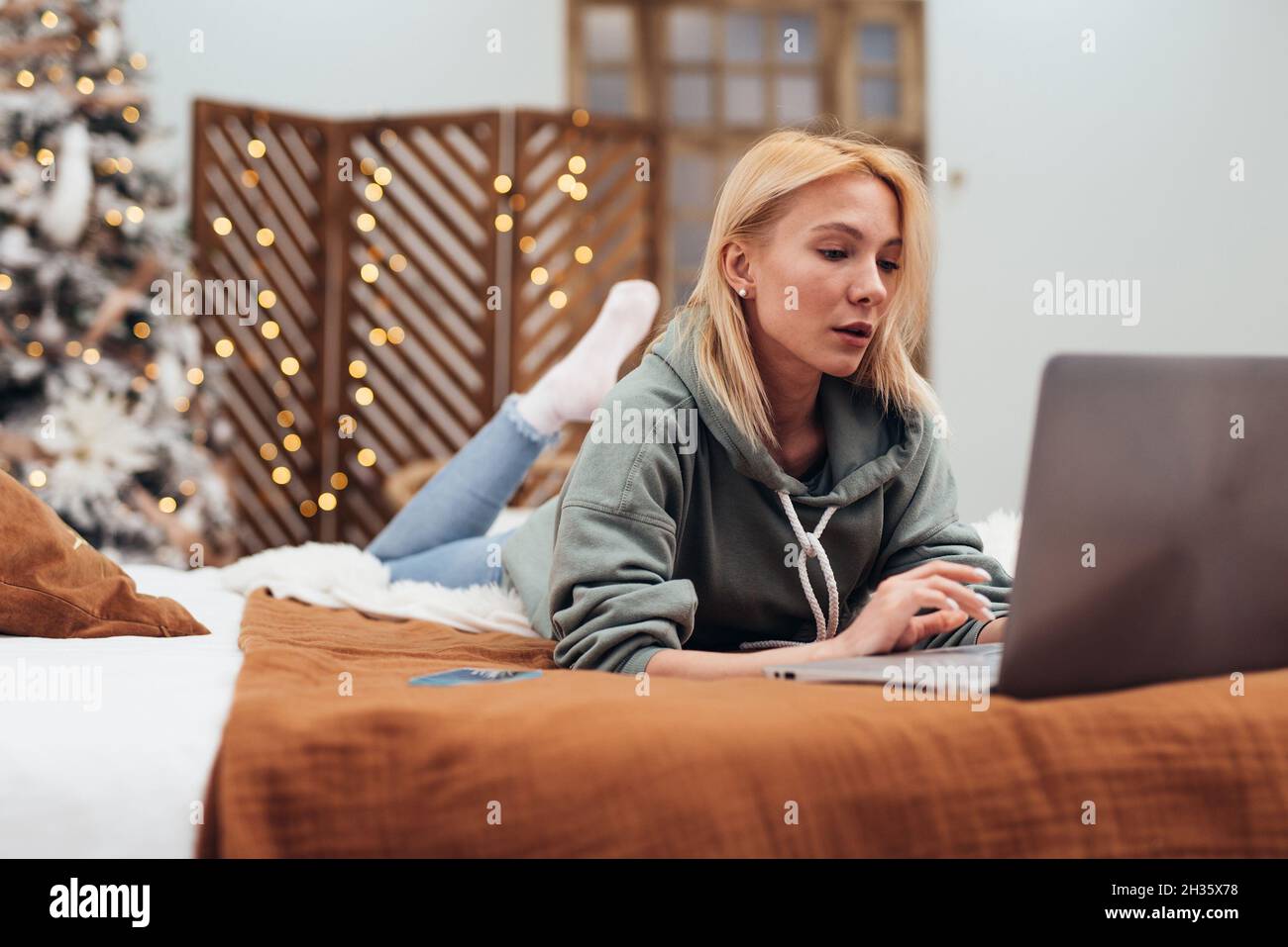 Young woman using laptop computer while lying on couch at home Stock ...