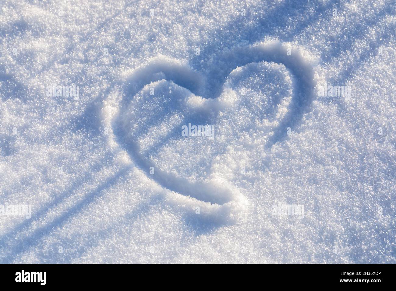 Heart drawing on white snow with diagonal dark blue shadows. Festive ...