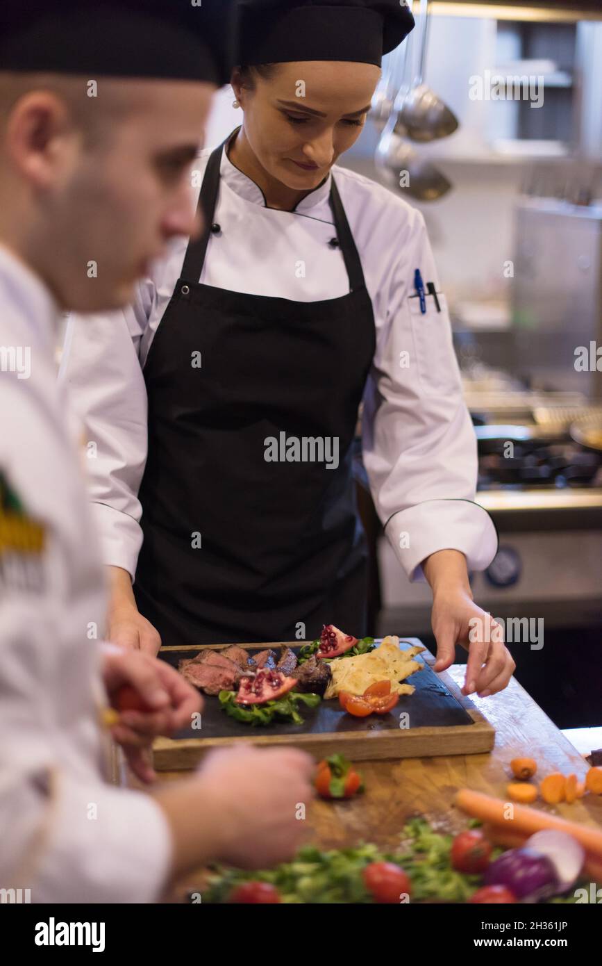 Professional team cooks and chefs preparing meal at busy hotel or ...