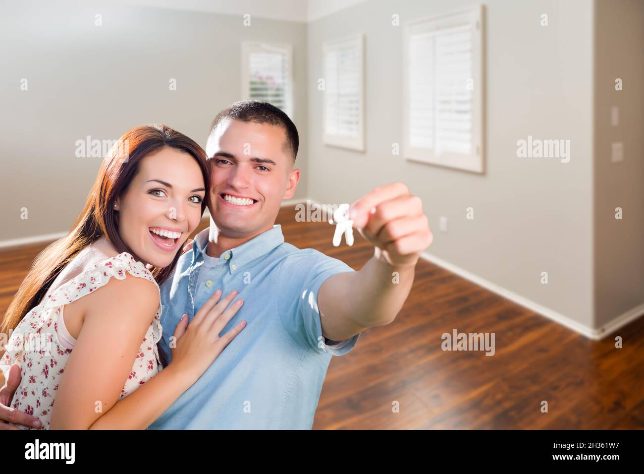 Young Military Couple Showing Off House Keys in Empty Room of New Home ...