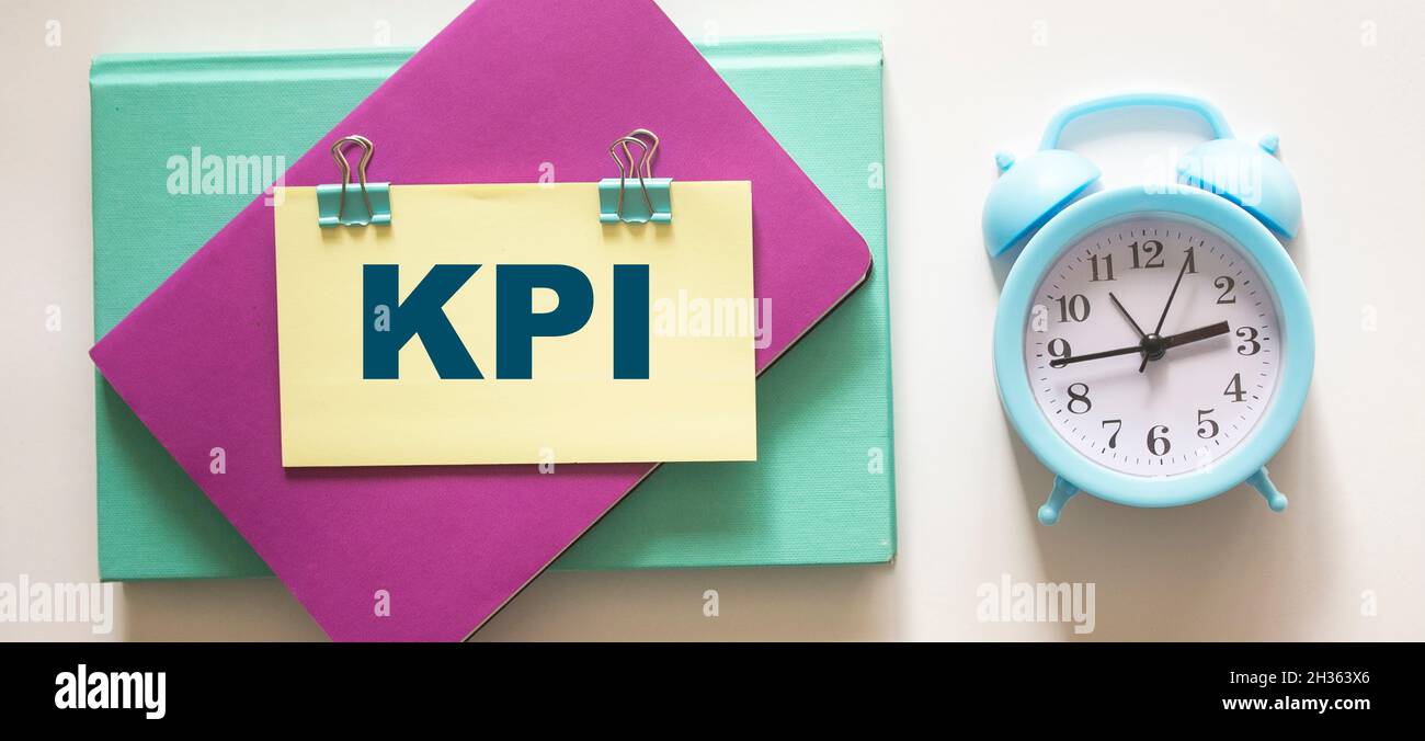 Colored notepads, alarm clock and sticker with KPI text on white background Stock Photo