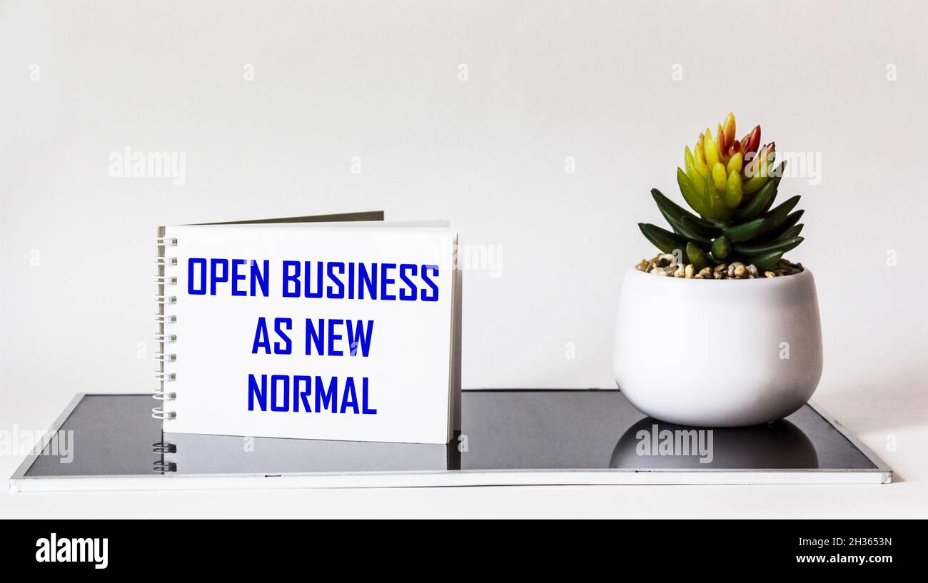 OPEN BUSINESS AS NEW NORMAL, text on notepad and white and black background. Stock Photo
