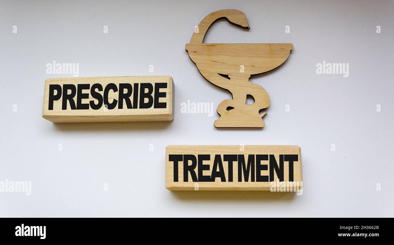 On a white background - medication icon and wooden blocks with the text Prescribe treatment Stock Photo