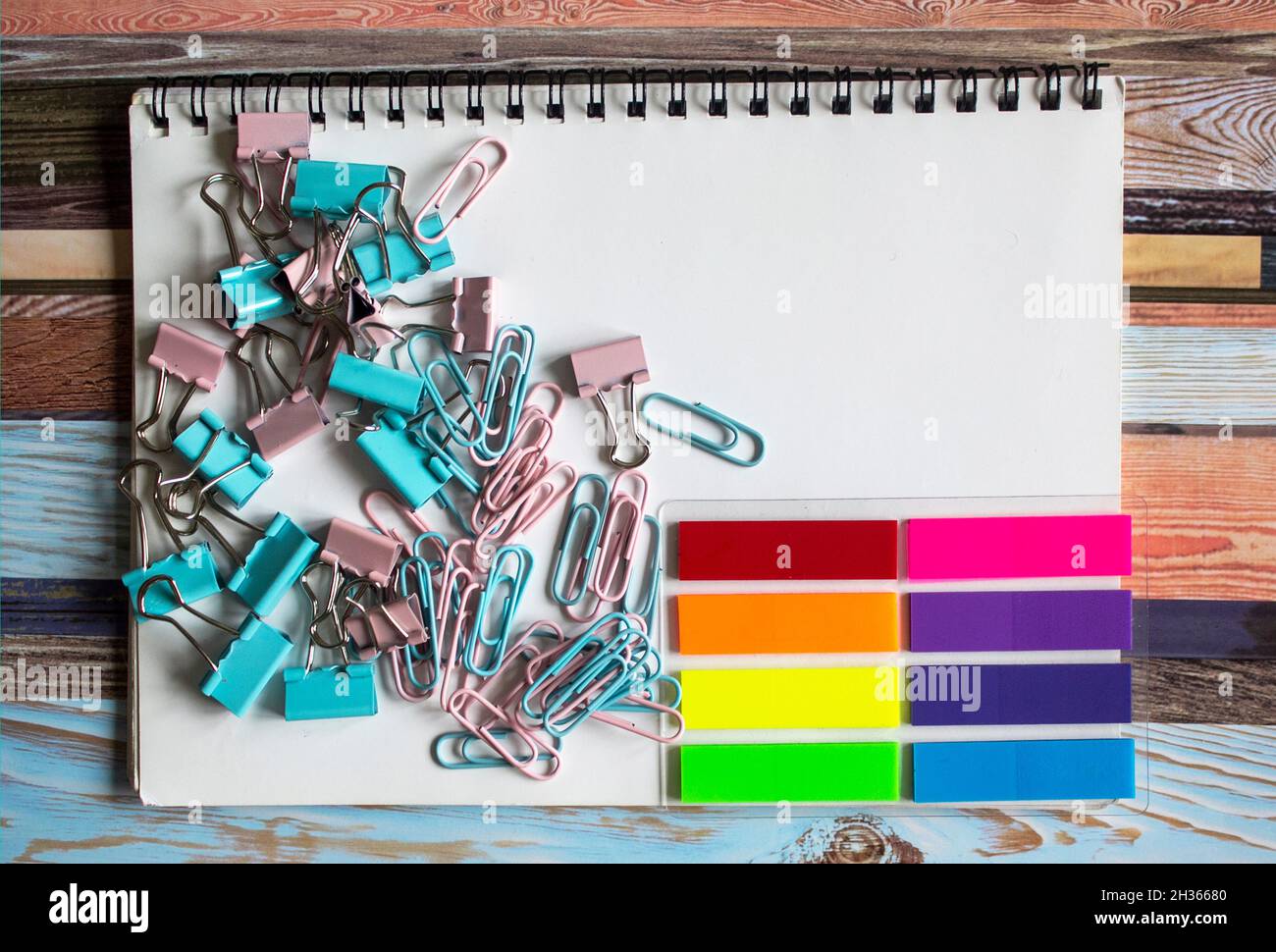 Collection of different types of paper clips on a white notepad and