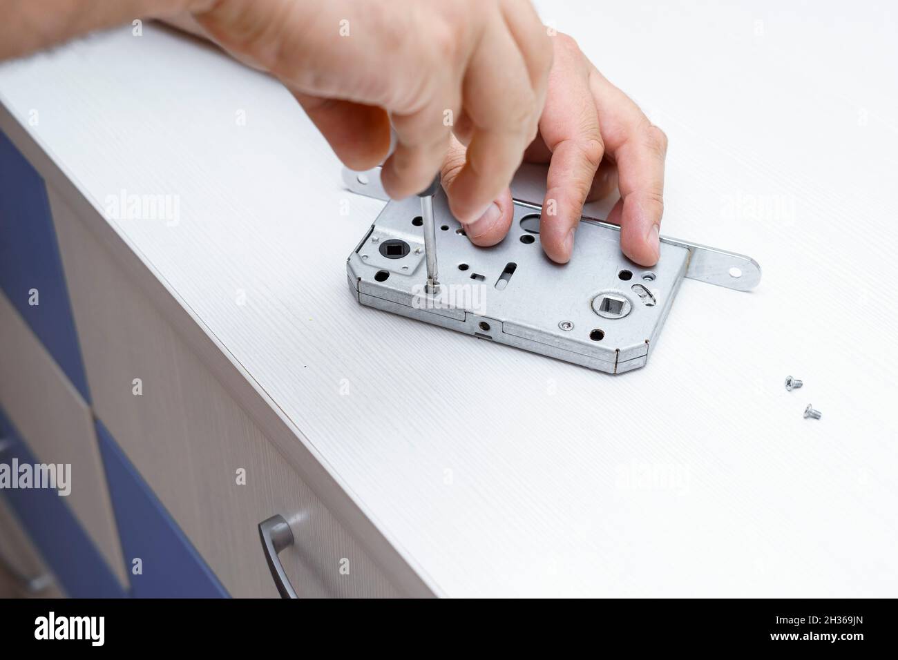 the master disassembles the door lock with a screwdriver Stock Photo