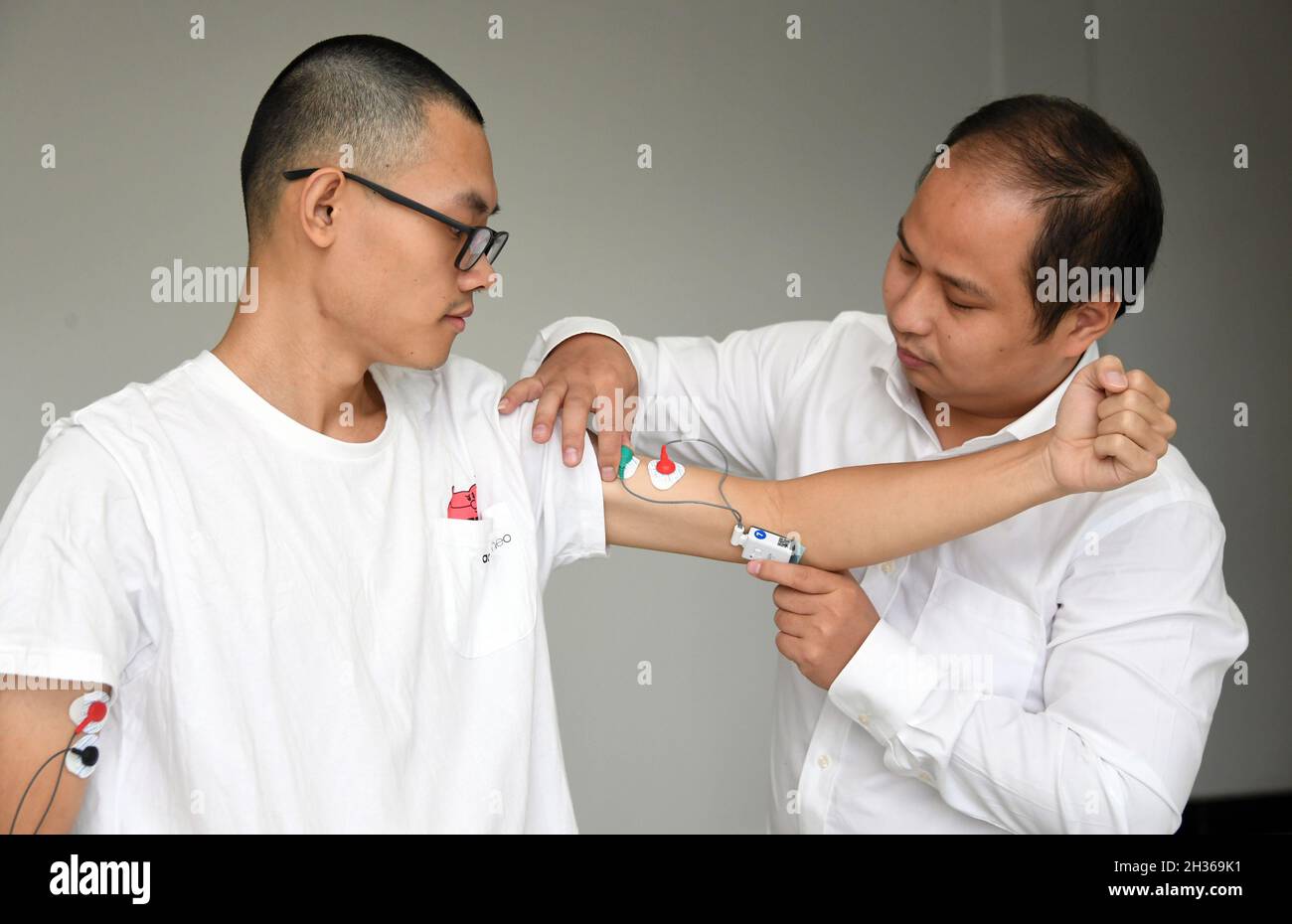Beijing, China. 14th Oct, 2021. Sun Qing (R), a student of Professor Huo Bo, puts on sensors on Huang Yi, also a student of Professor Huo, at the School of Astronautics, Beijing Institute of Technology, in Beijing, capital of China, Oct. 14, 2021. TO GO WITH 'China Focus: Smart tech serves as coaches for Beijing 2022 athletes' Credit: Ren Chao/Xinhua/Alamy Live News Stock Photo