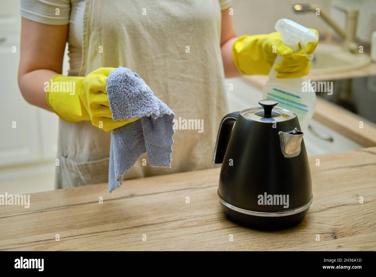 A woman wipes an electric kettle with a rag when cleaning a home ...