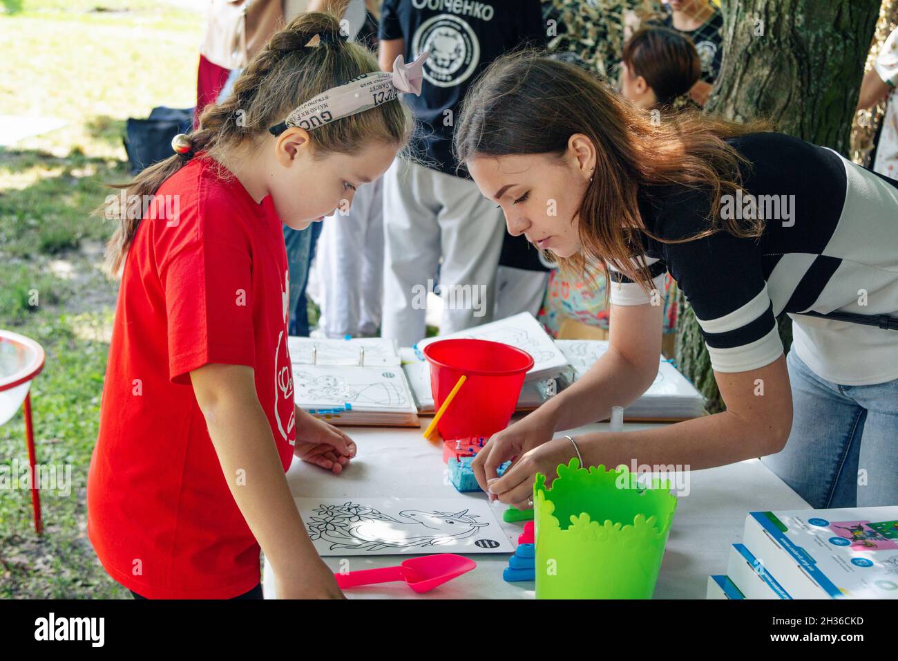 Zaporizhia, Ukraine- June 19, 2021: Charity Family festival:  woman – volunteer explaining to a girl how to paint the picture at art and craft outdoor Stock Photo