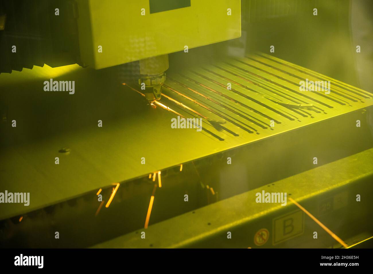a robotic laser cutter is cutting holes in a steel part at a