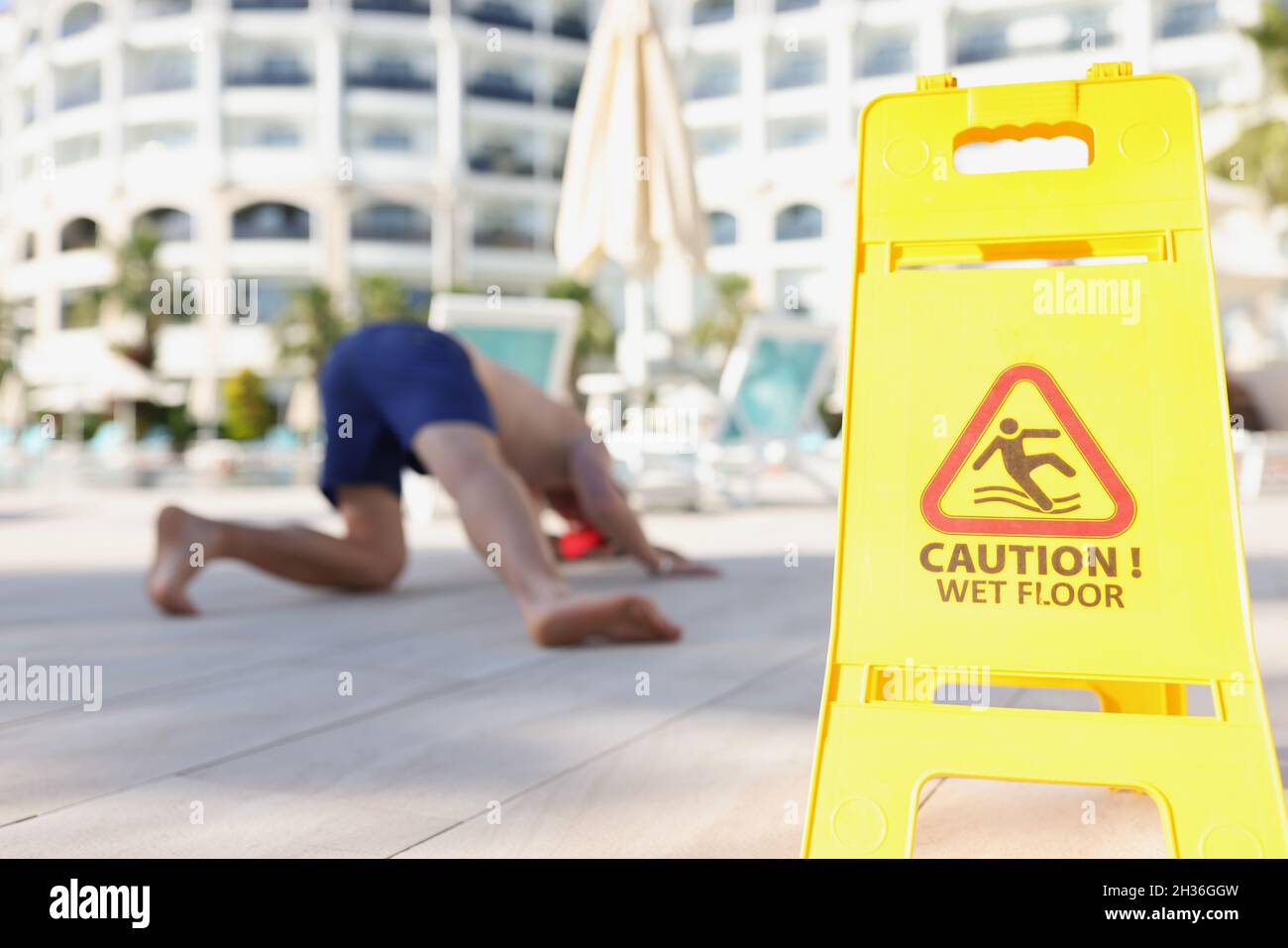 Yellow sign with warning caution wet floor standing near falling man closeup Stock Photo
