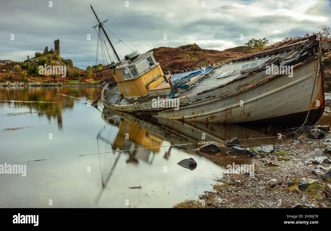 Abandoned boat on Loch Alsh, Isle of Skye, Scotland, with the ruins of Castle Moil in the background Stock Photo