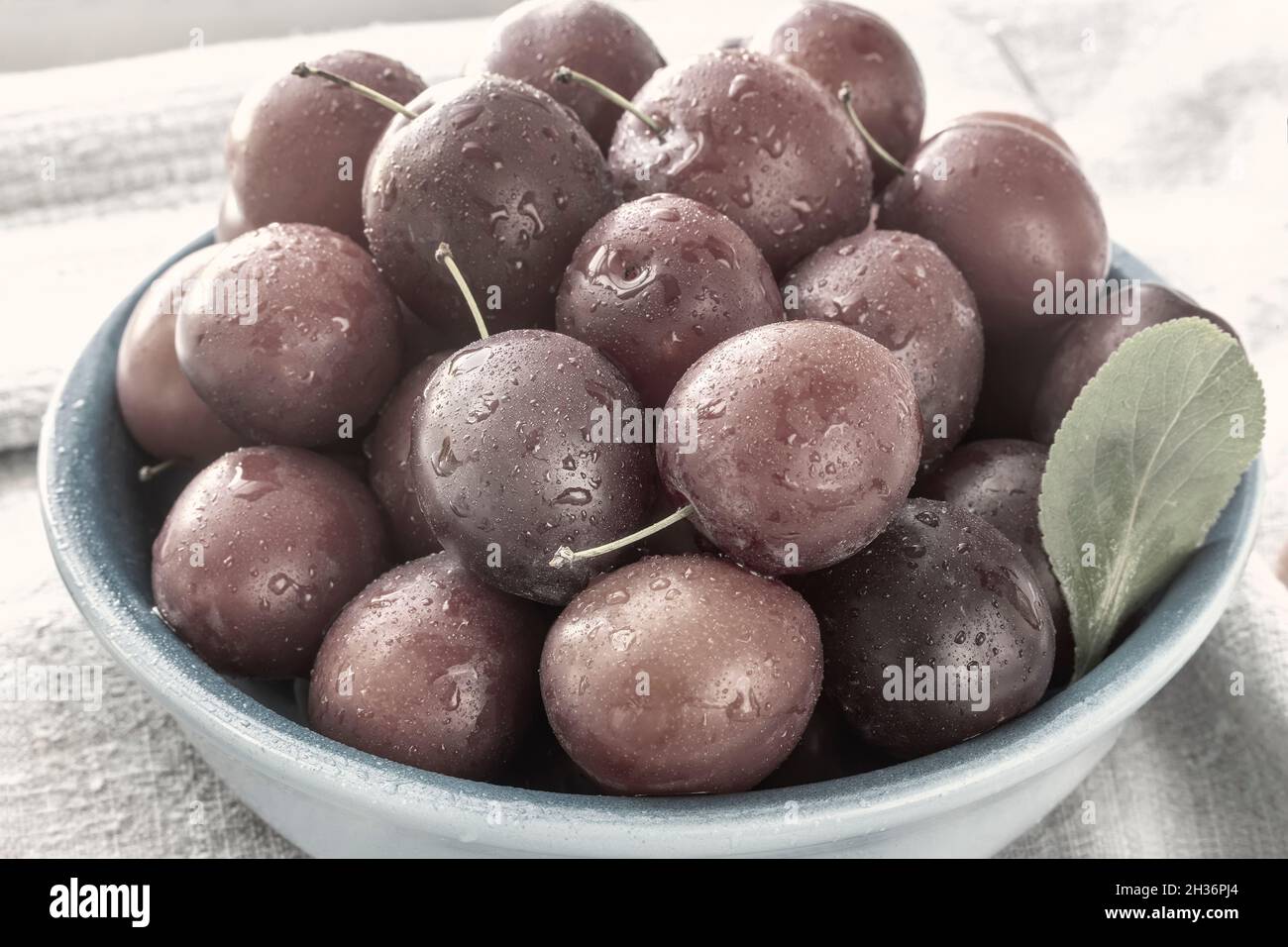 Ripe red plums in a blue ceramic plate Stock Photo