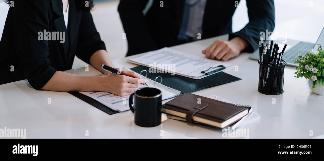 Close up of young business people analyzing data from paperwork using computer while working in the office. meeting discussion concept Stock Photo