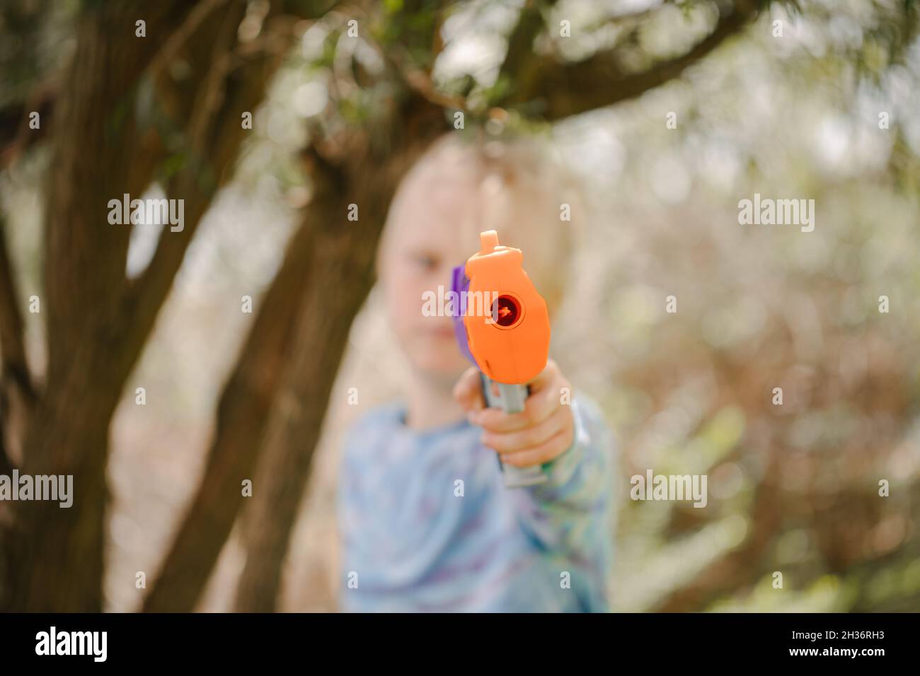 Boy holding toy nerf gun directly in front obscuring his face Stock Photo