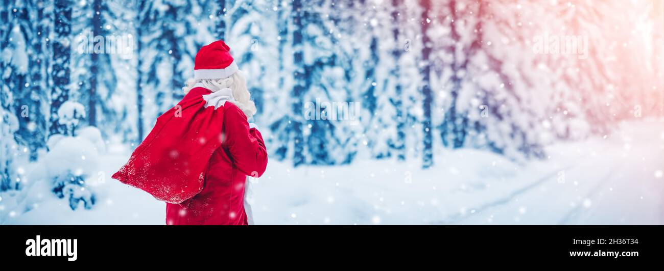 Santa Claus with sack of presents walking in the snowy winter forest Stock Photo