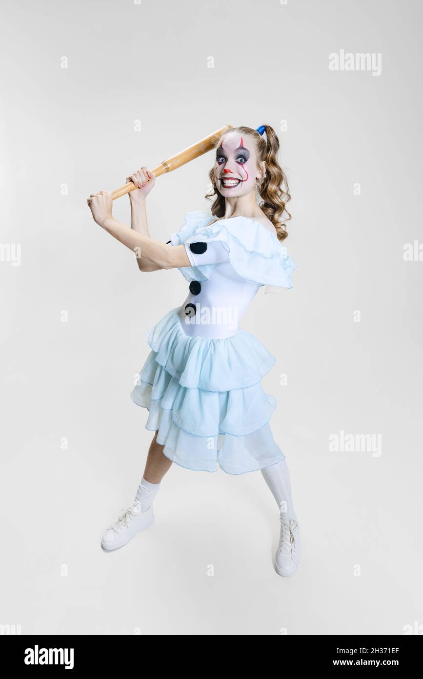 Halloween spooky theme. Portrait of beautiful artistic girl in halloween make-up and costume of dancing clown isolated over grey background Stock Photo