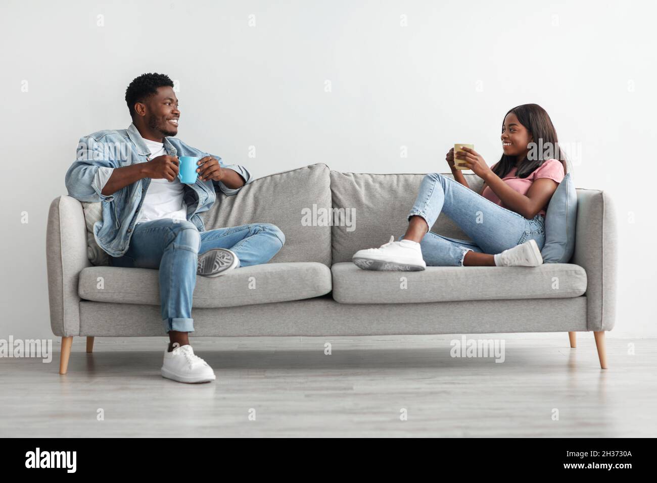 African american couple drinking coffee sitting on couch Stock Photo ...
