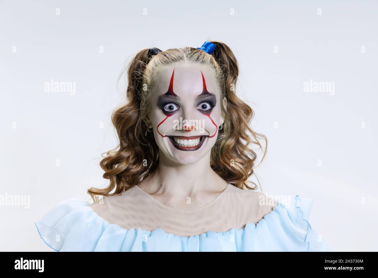 Close-up mystical blonde girl with halloween bright make-up and spooky facial expression looking at camera Stock Photo