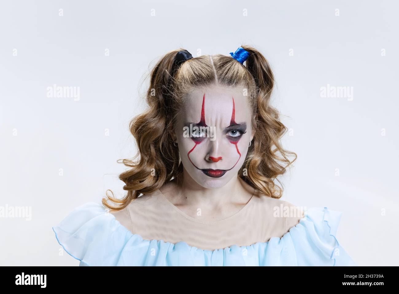 Close-up mystical blonde girl with halloween bright make-up and spooky facial expression looking at camera Stock Photo